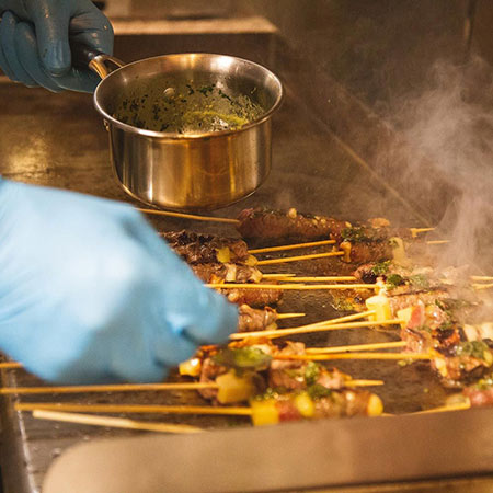 Dual fuel gas griddle with skewers and vegetables grilling on heated surface