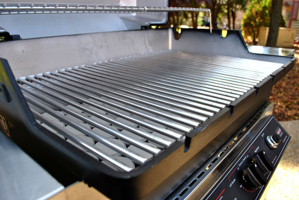 Gas grill open lid showing stainless cooking grates and control panel