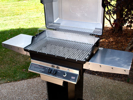 Built-in gas grill with open lid, side shelf, and grates